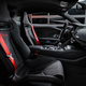 the interior of the 2023 audi r8 gt, upholstered entirely in black leather with red seat belts and red stitching on the seats that spells out 'r8 gt'